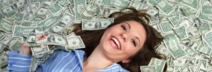 A happy woman lying on a pile of money