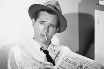 A man reading a newspaper with a quizzical but confident look.